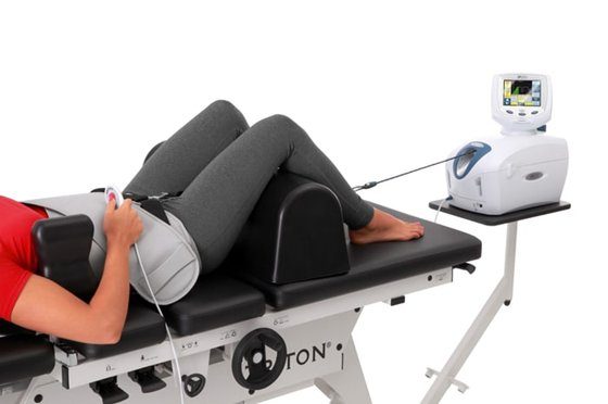 A patient lying on their back on a modern spinal decompression table