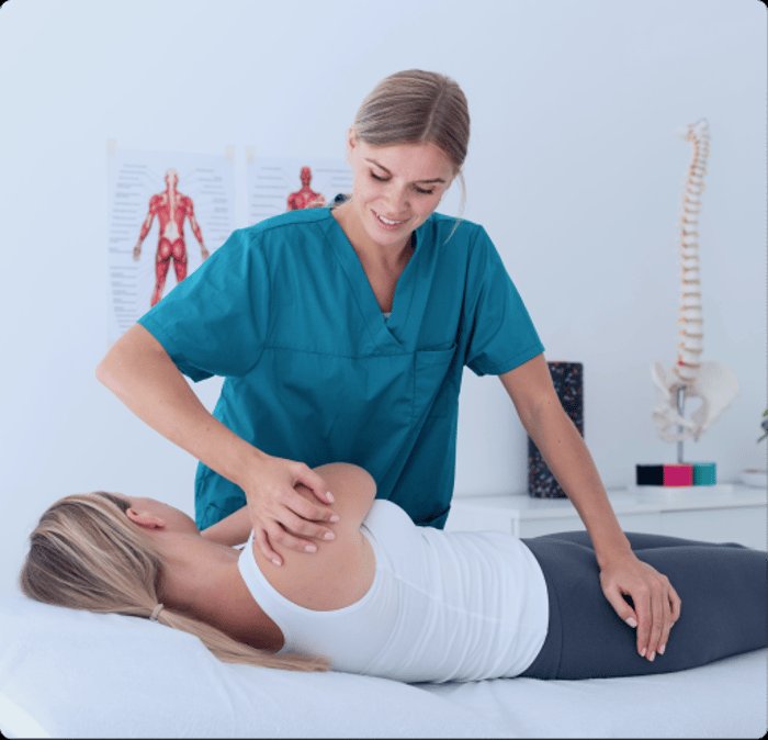 A smiling female physical therapist assisting a female patient with a guided leg stretch on a treatment table in a clinical setting