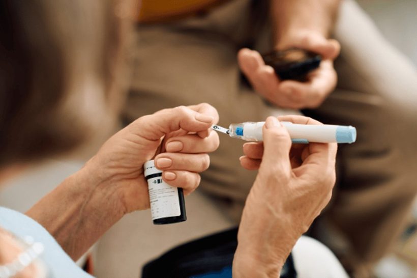 Close-up of hands holding an insulin pen, preparing for an injection.