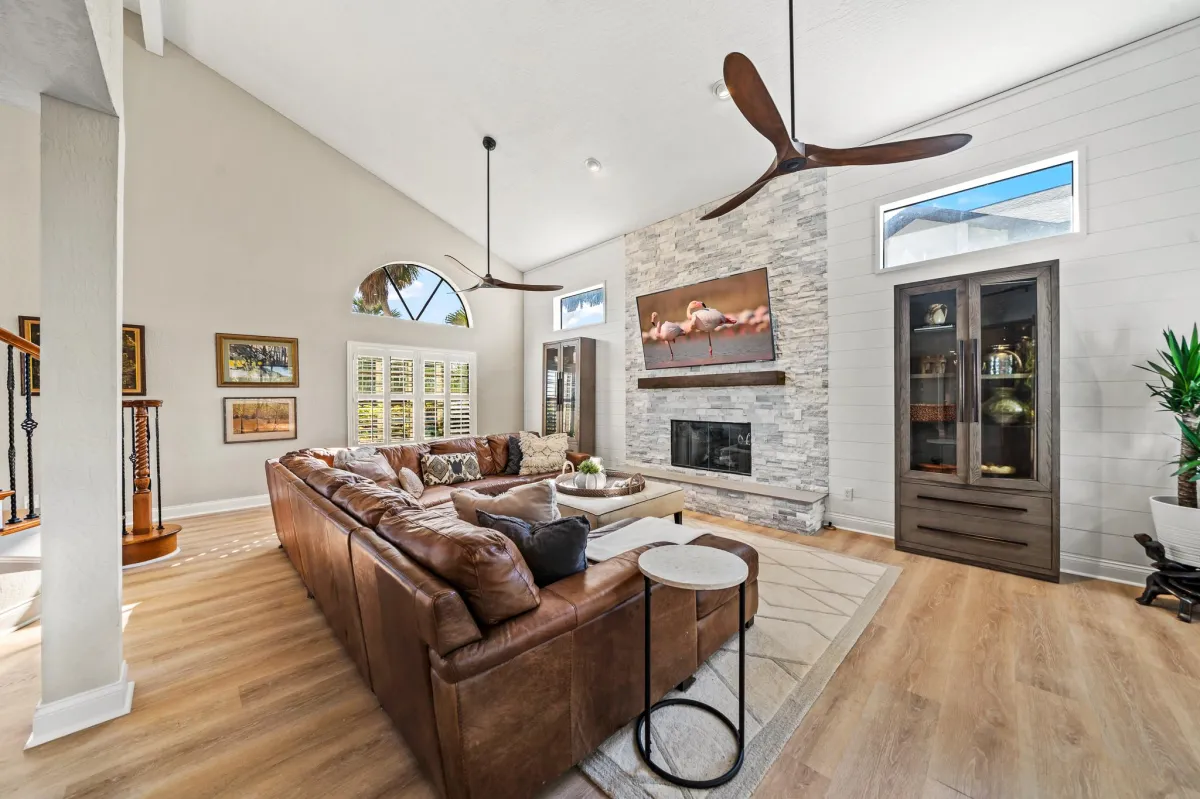 Living room with stone fireplace and vaulted ceilings in riverfront estate
