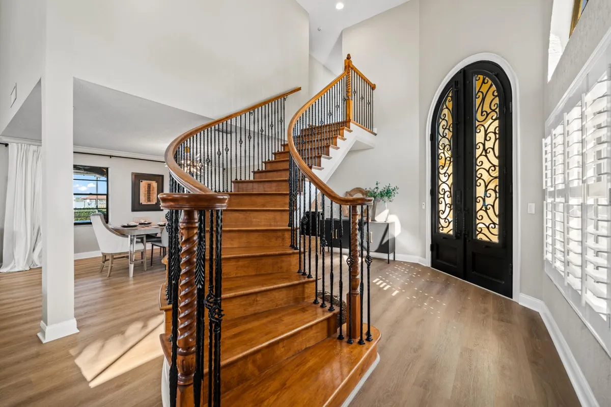 Grand staircase with wood and wrought-iron railing in luxury foyer