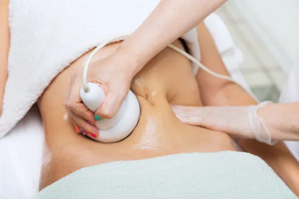 Non-surgical body contouring treatment being performed on a client's abdomen