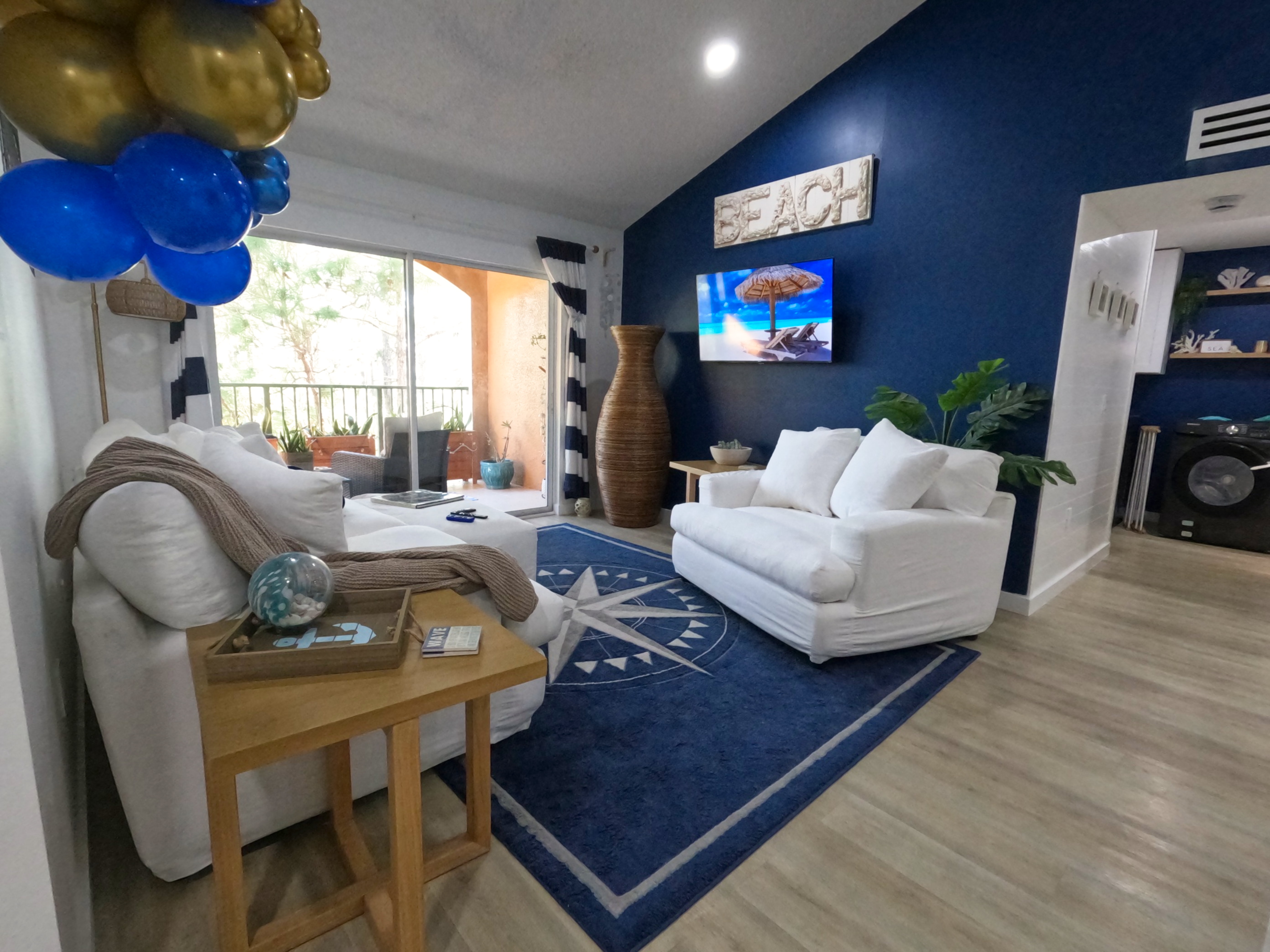 Living Room Cozy Nook: "Navy blue sofa and bright white accents in beachy living room of 2BR monthly condo rental Naples FL, perfect for relaxed snowbird evenings."