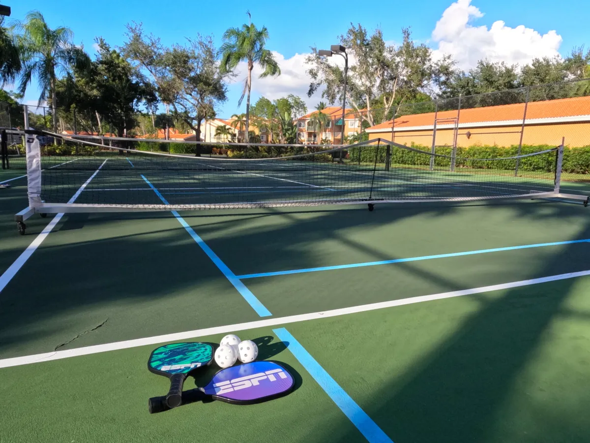Pickleball Action Shot: "Friends playing pickleball on community courts near Royal Palm Retreat, fun seasonal events for extended stay guests in Naples FL."