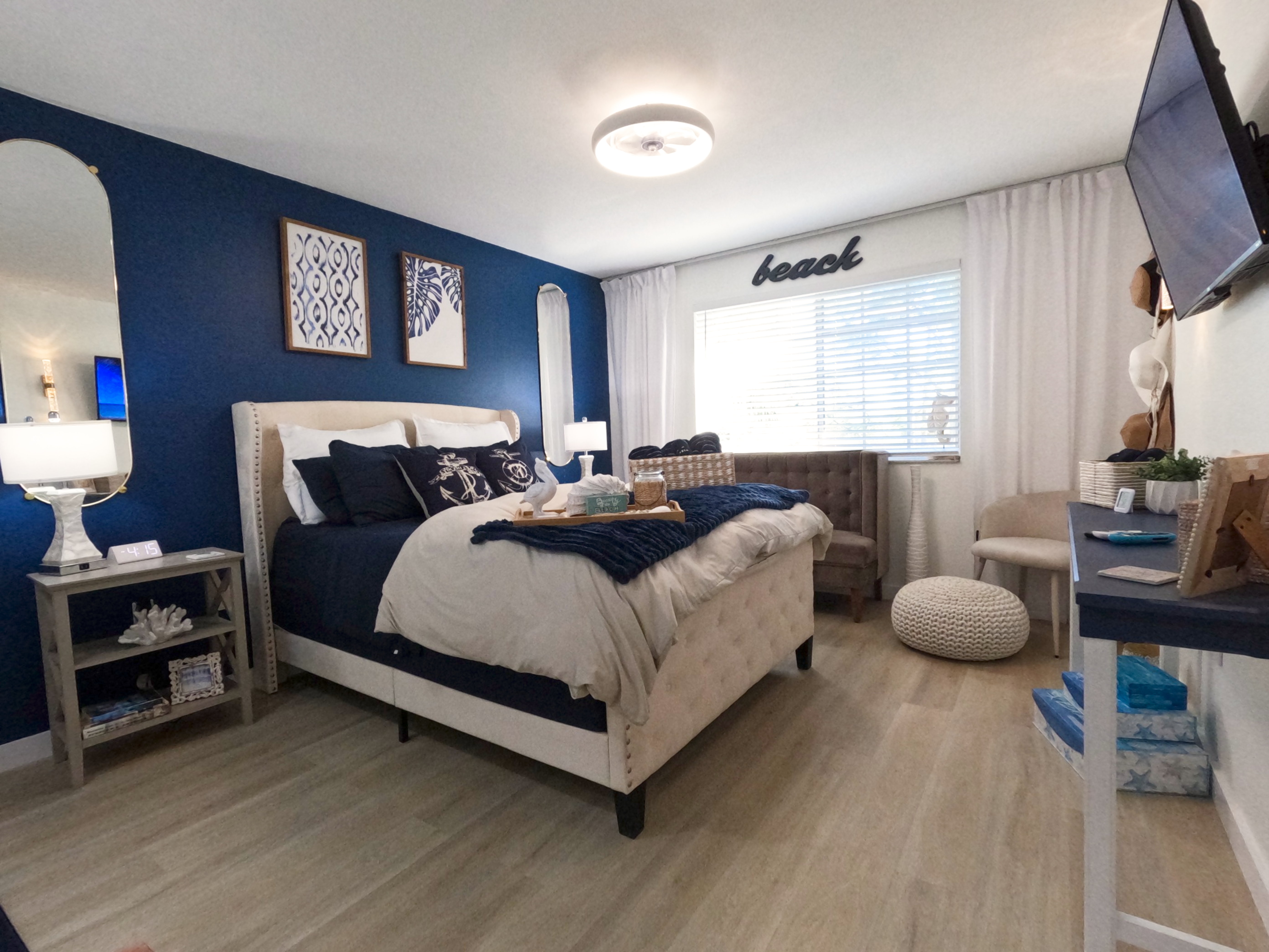 Master Bedroom Retreat: "Serene master bedroom with navy blue headboard and white linens in beach-themed 2BA condo, extended stay comfort in Naples Florida."