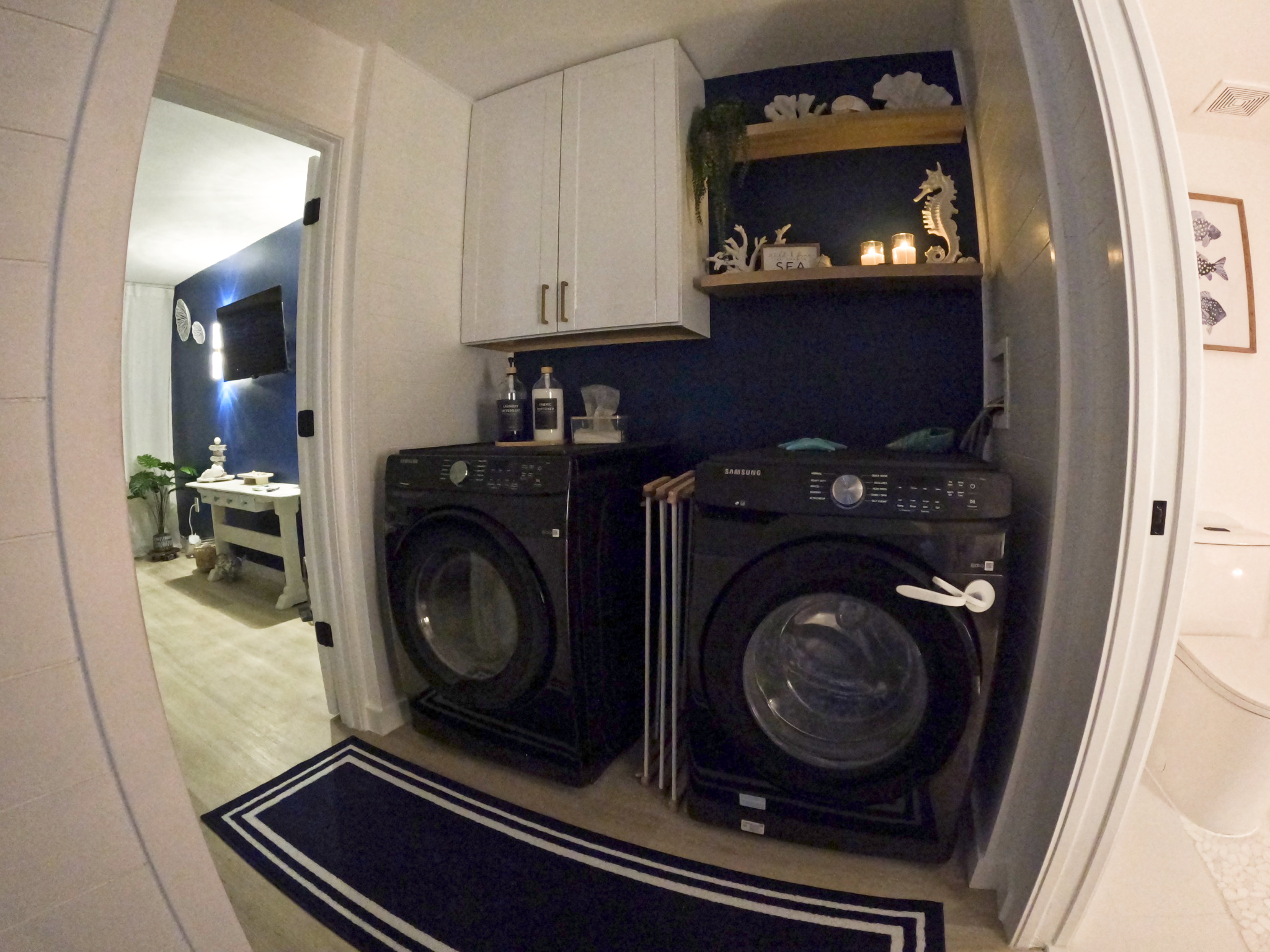 "Full-size washer & dryer in navy blue & white beach-themed laundry room, in-unit convenience for snowbird monthly rentals Naples FL"