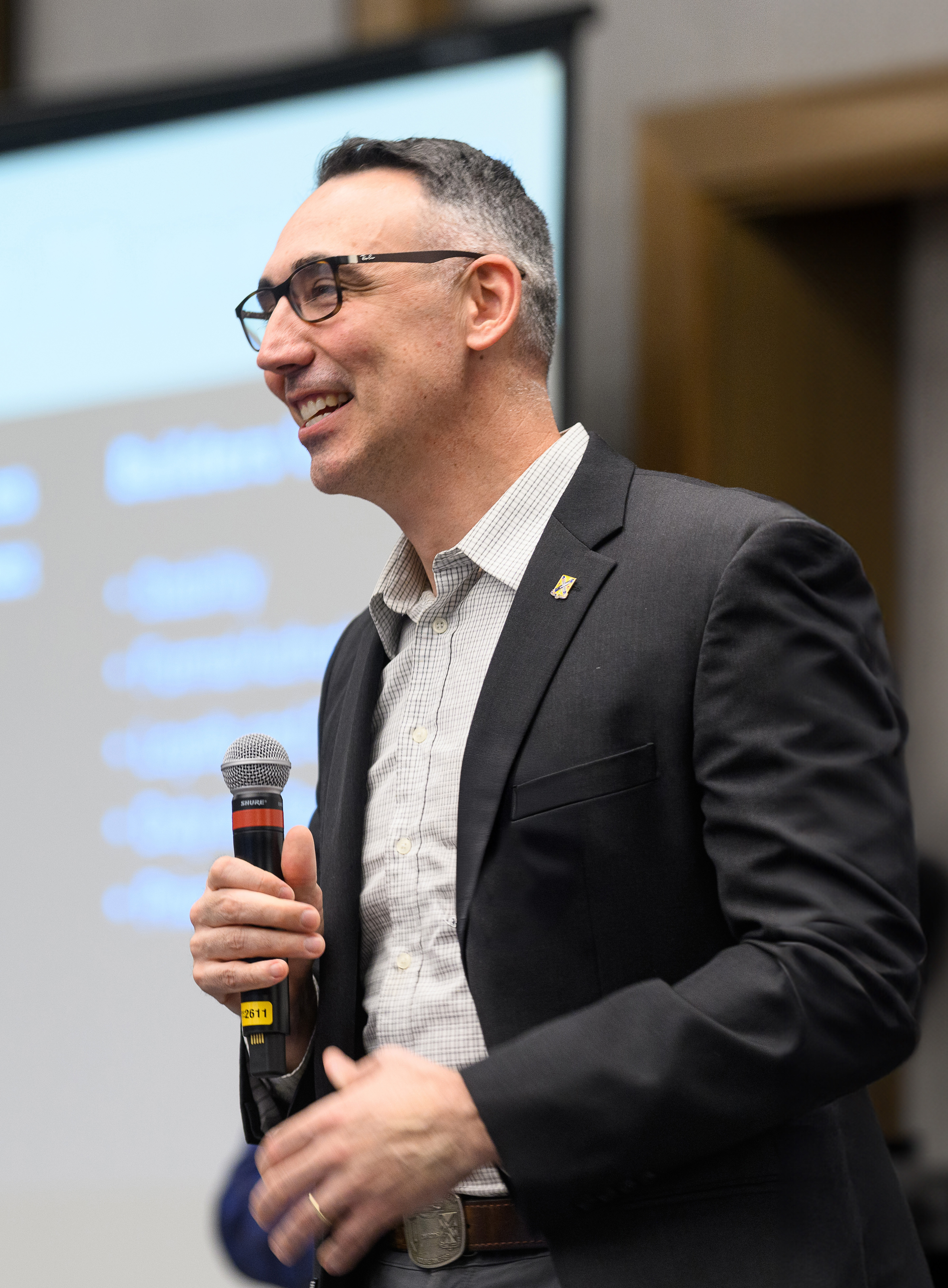 A professional leadership facilitator in action, high contrast, desaturated with subtle gold highlights.