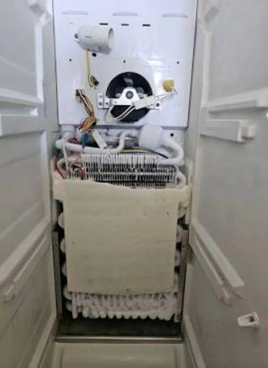 Inside view of refrigerator compressor and cooling system under repair by Sammy Appliance Repair in Queens
