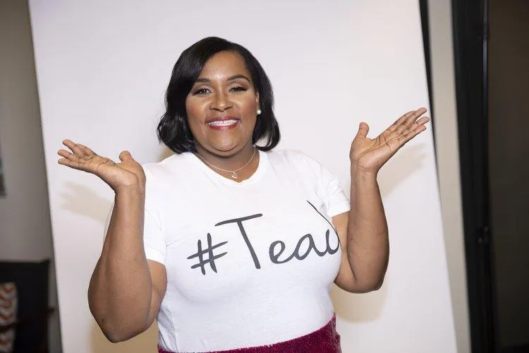 Young boy smiles at desk with laptop and chalkboard.
