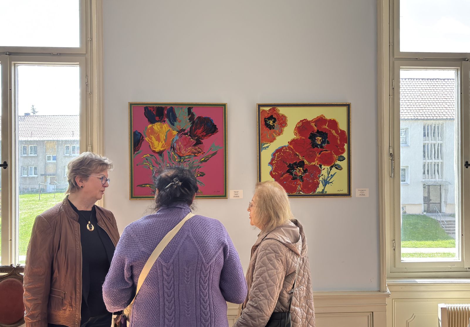 Besucherinnen im Gespräch vor floralen Öl-Gemälden von Christine Graf in der Favori Art Ausstellung „Favori No.1 – GENESIS“ im Schloss Gleina.