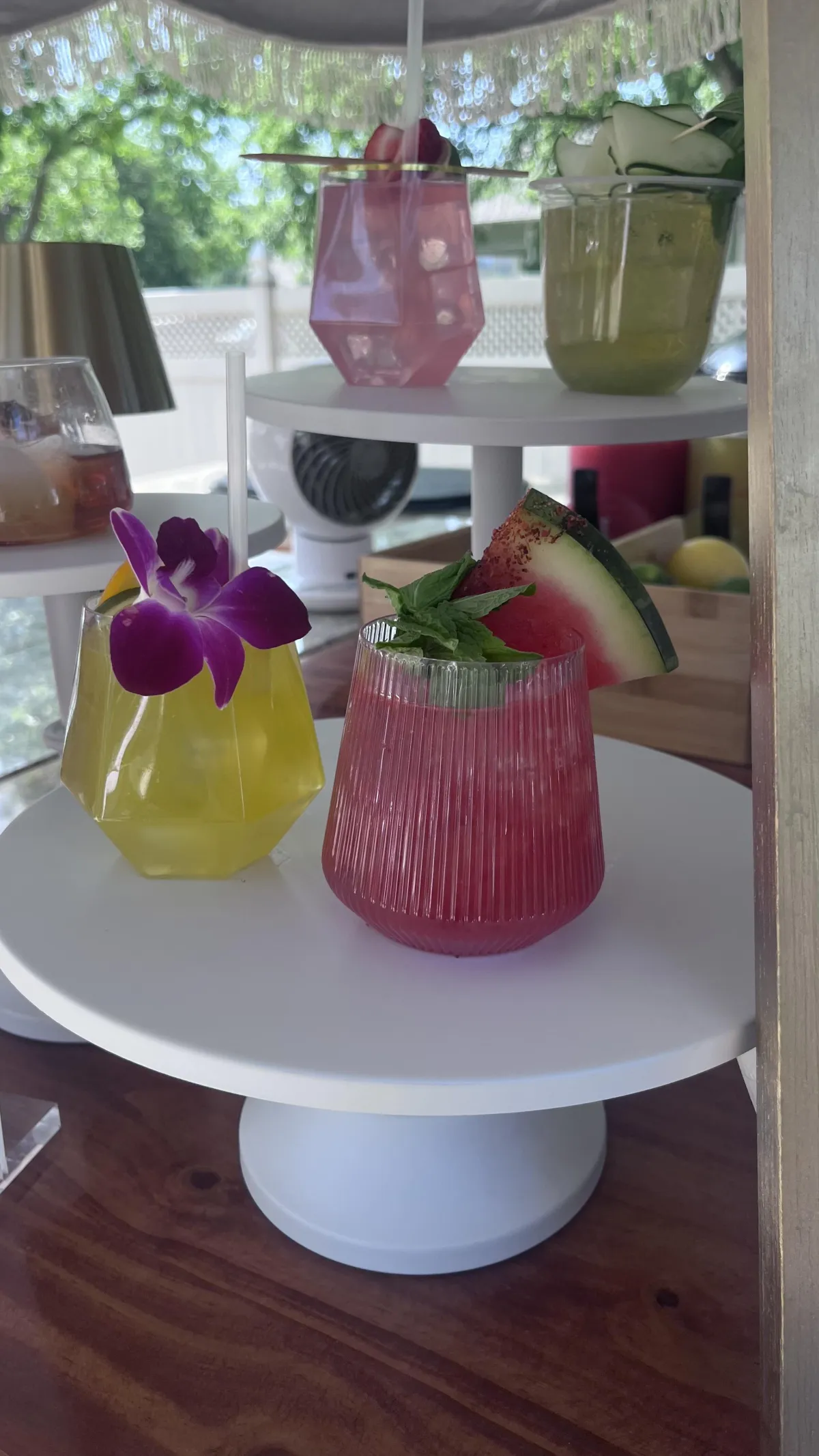 Colorful signature wedding cocktails prepared by a professional bartender at the Shake Rattle & Roll mobile bar, featuring vibrant garnishes like orchid, mint, and watermelon on display