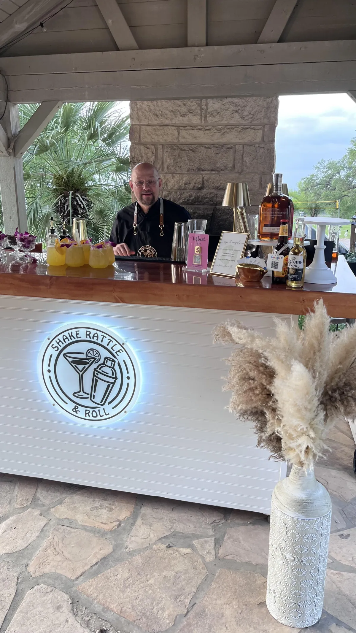 Professional bartender serving drinks at a Shake Rattle & Roll mobile bar during a private party in San Antonio, with craft cocktails and premium liquor on display.