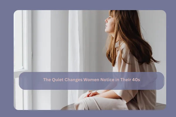 Professional woman in her 40s sitting by a window in soft natural light, looking thoughtful and reflective, representing subtle internal changes in energy and focus during midlife.
