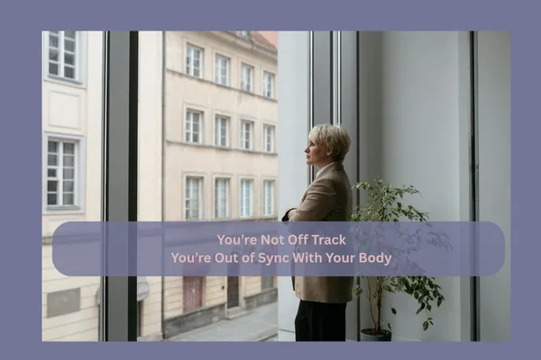 Successful woman pausing and looking out her office window with a thoughtful expression, feeling something is off despite continuing to perform at a high level.