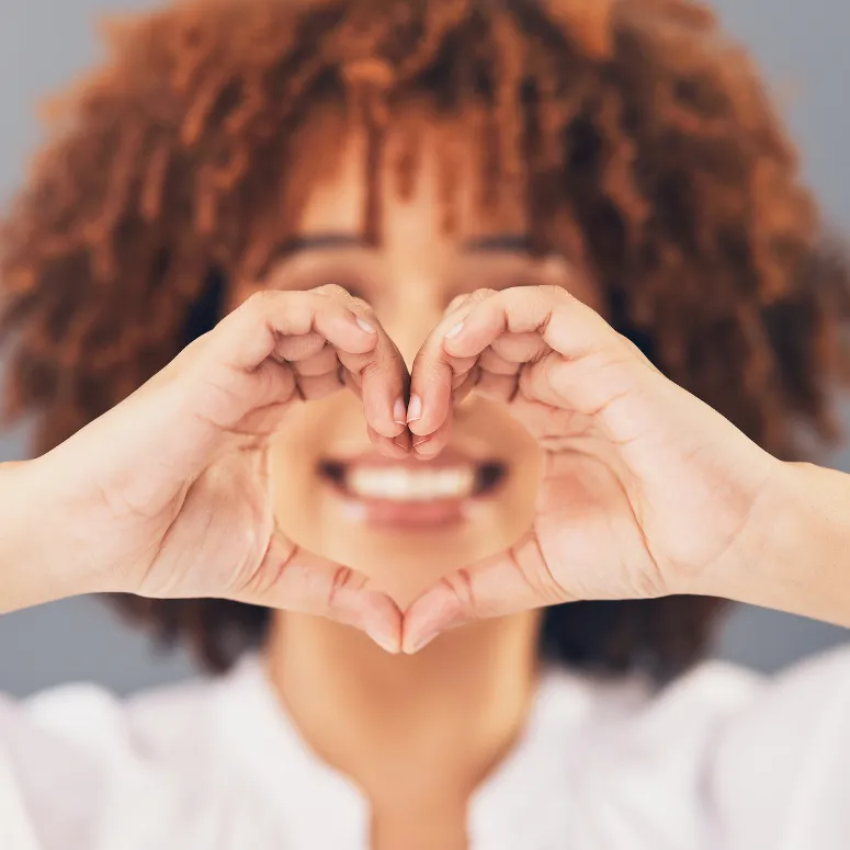 Woman smiling making a heart sign with her hands