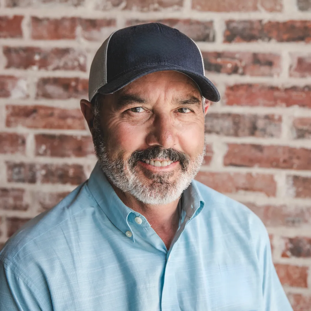Headshot Of Cecil Price Smiling In Light Blue Shirt And Cap Leadership Team At 8:12 Roofing And Exteriors