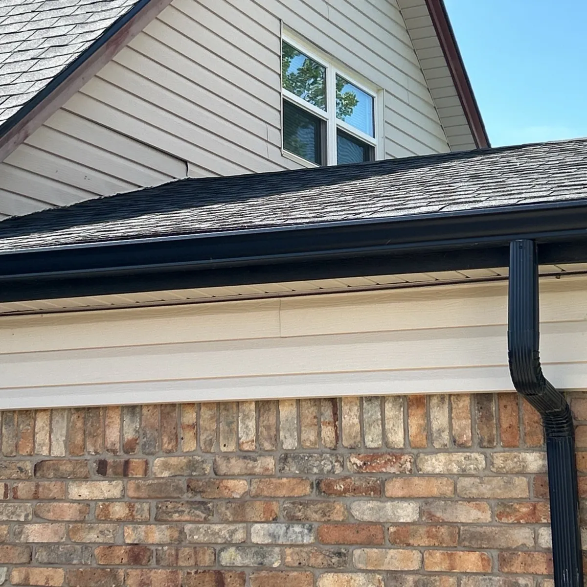 Beige Vinyl Siding With Brick Accent and Gutter Downspout