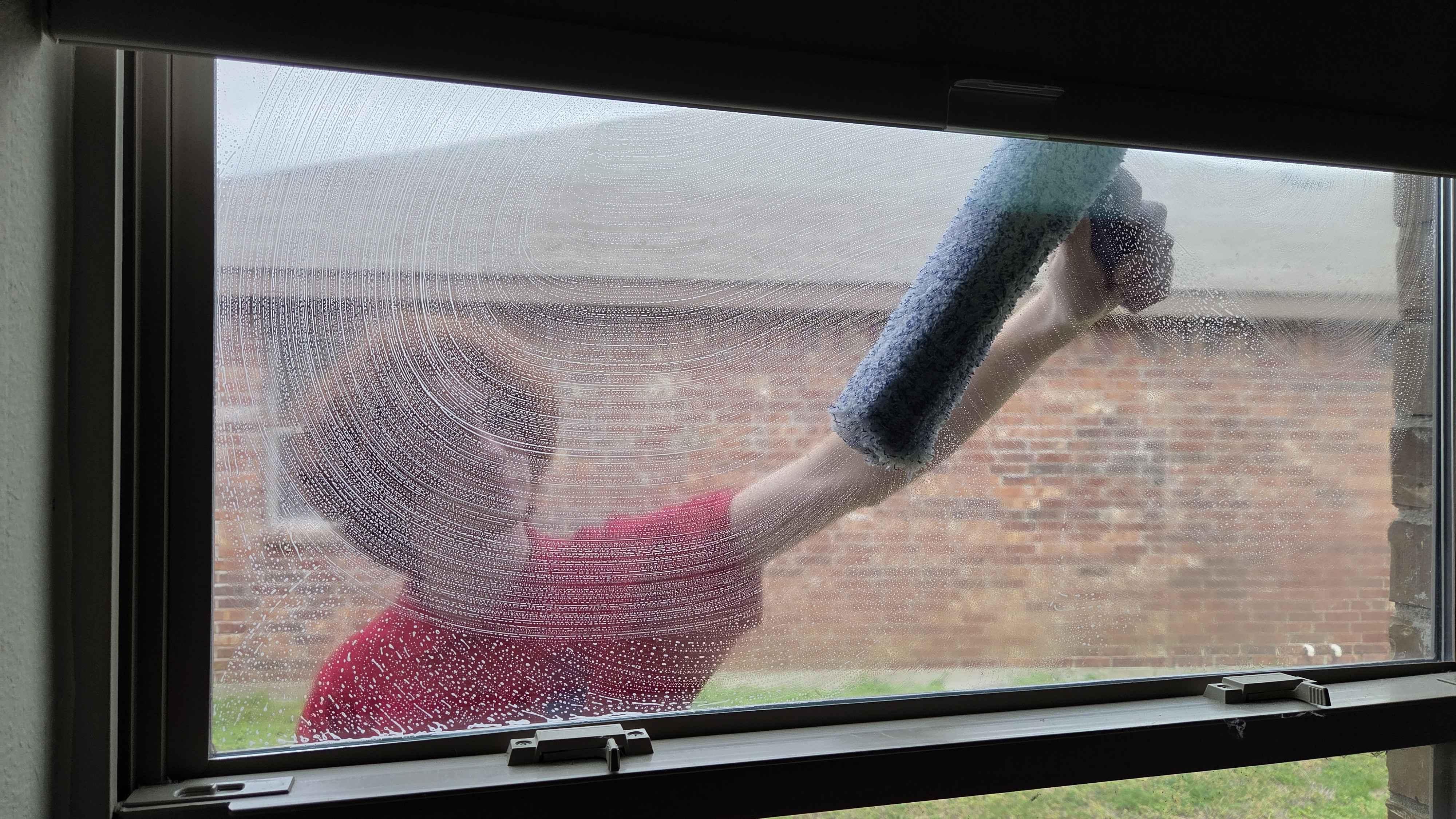 Technician cleaning residential windows in Hunt County