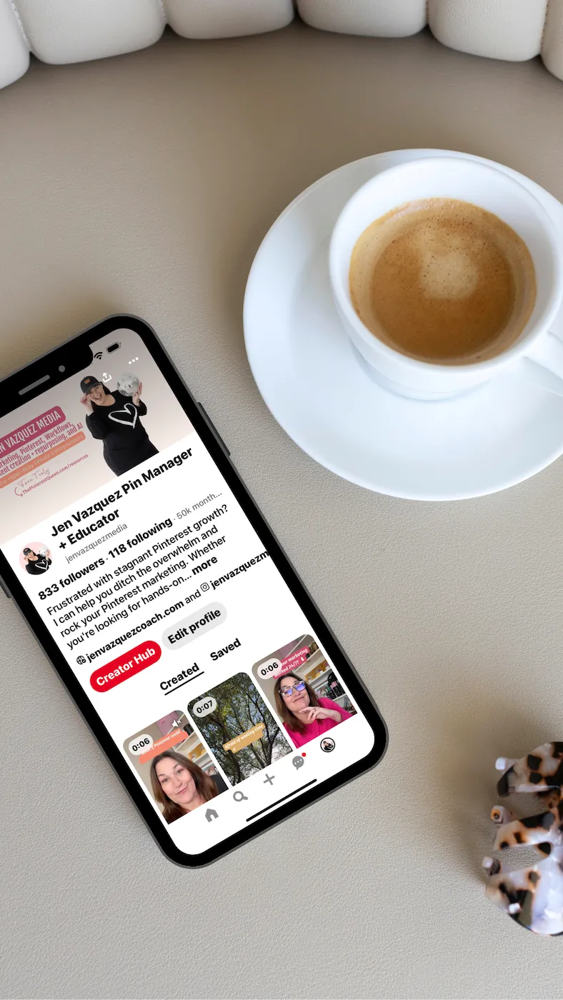 Pinterest on cell phone with cup of tea and hair clip on chair