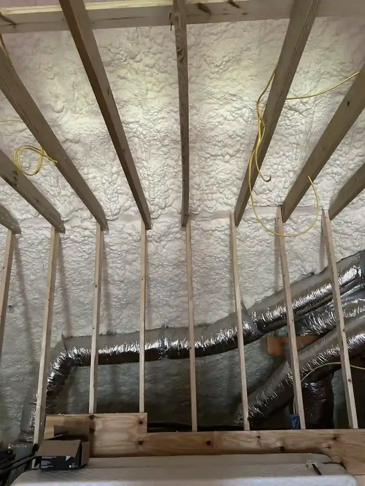 Attic with open cell spray foam insulation enhancing energy efficiency and air sealing for residential comfort.