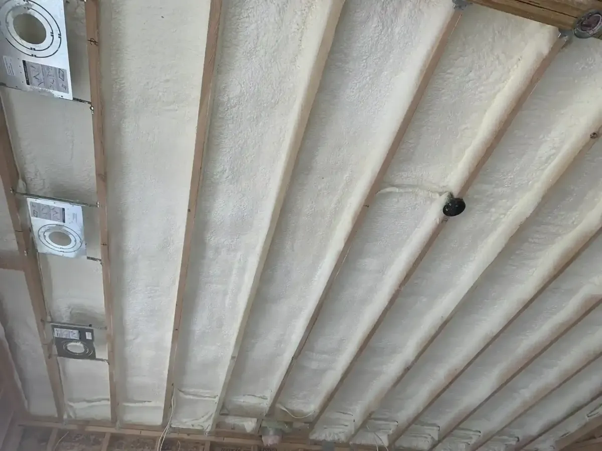 Closed cell spray foam insulation applied between ceiling joists in a pole barn near Raleigh, NC, showcasing superior moisture control and structural strength for metal building efficiency.
