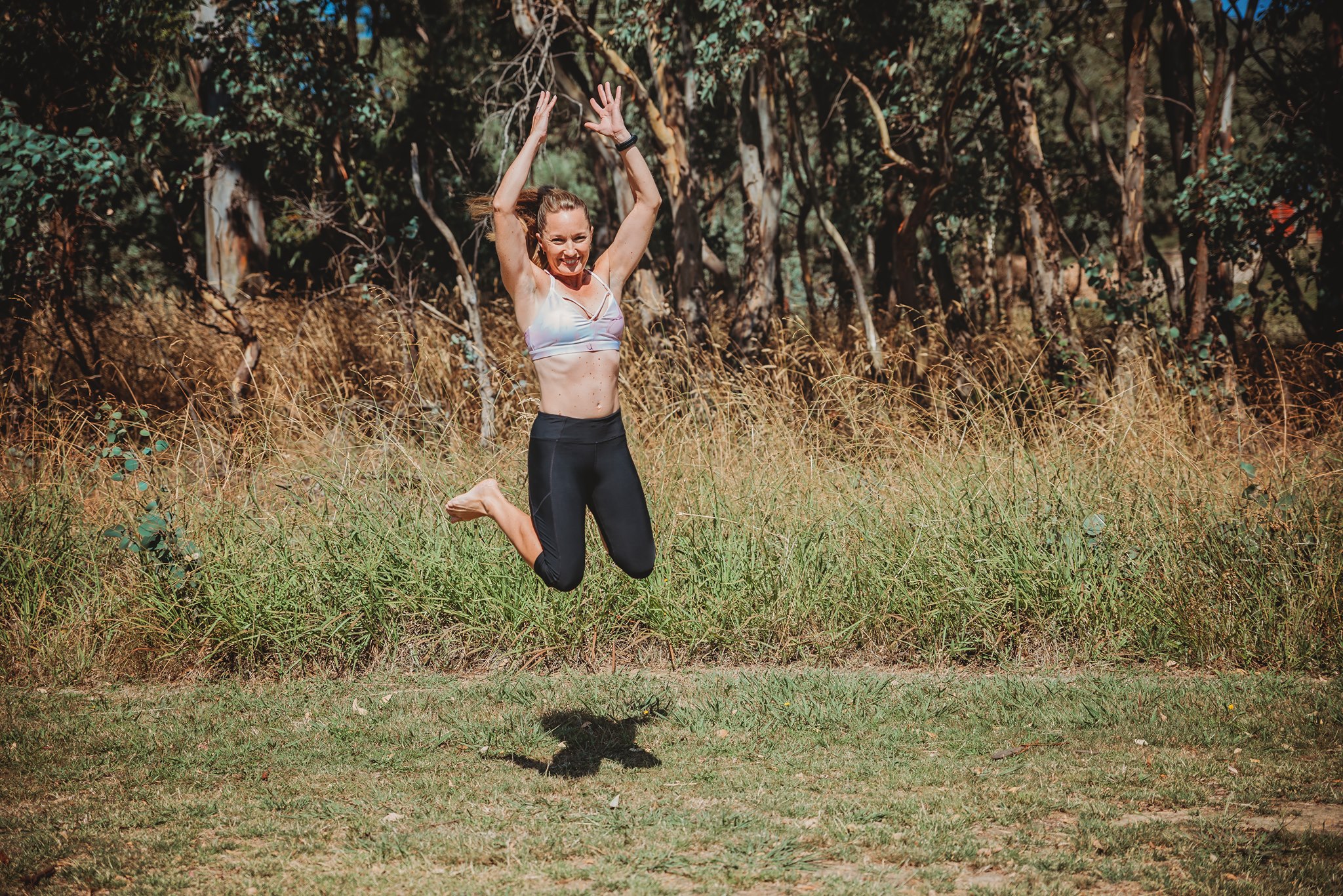 A diverse group of adults in modern activewear, mid-motion in a bright, minimalist gym, smiling and supporting each other during a group fitness session. The background is softly blurred, emphasising energy and camaraderie. Clean, contemporary style, 3:2 aspect ratio.