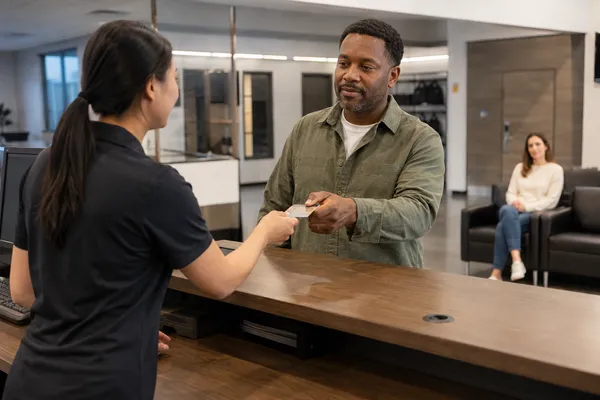 Customer presenting identification for a firearm pickup while a companion waits separately