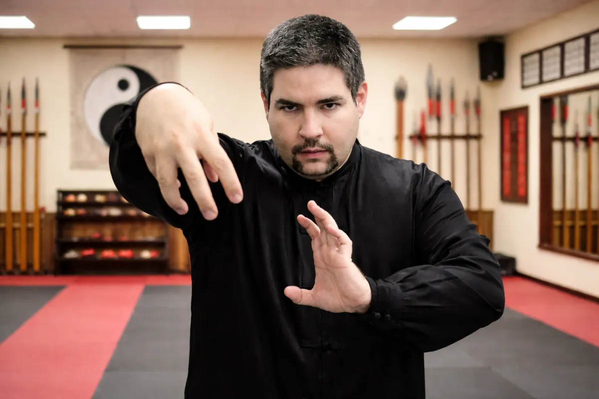 Grandmaster David Harris performing a specialized Shun Shen Tao hand strike technique in a training hall with a Yin Yang backdrop.