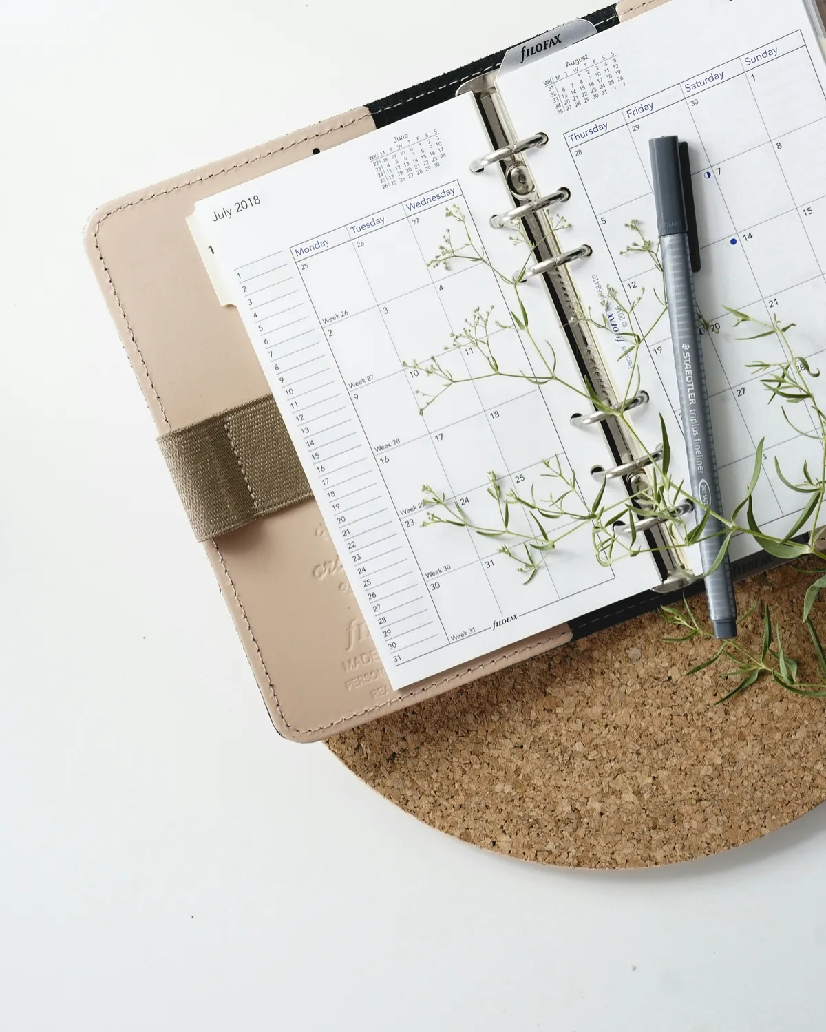 Agenda abierta con calendario, bolígrafo y elementos de escritorio.