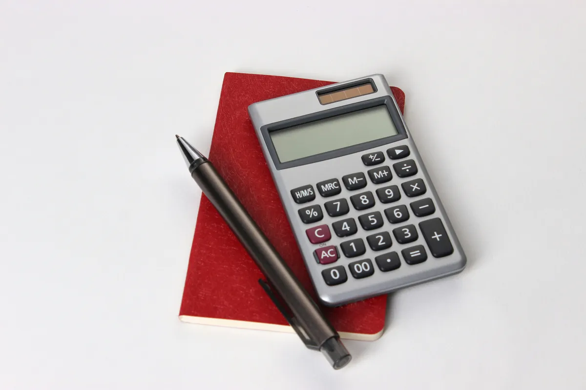 Calculadora y bolígrafo sobre un cuaderno rojo para organizar cuentas.