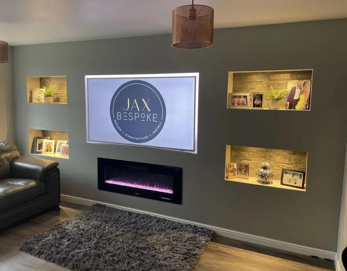 Grey media wall with electric fireplace and spot lighting illuminated tiled stoneeffect alcoves, featuring mounted TV