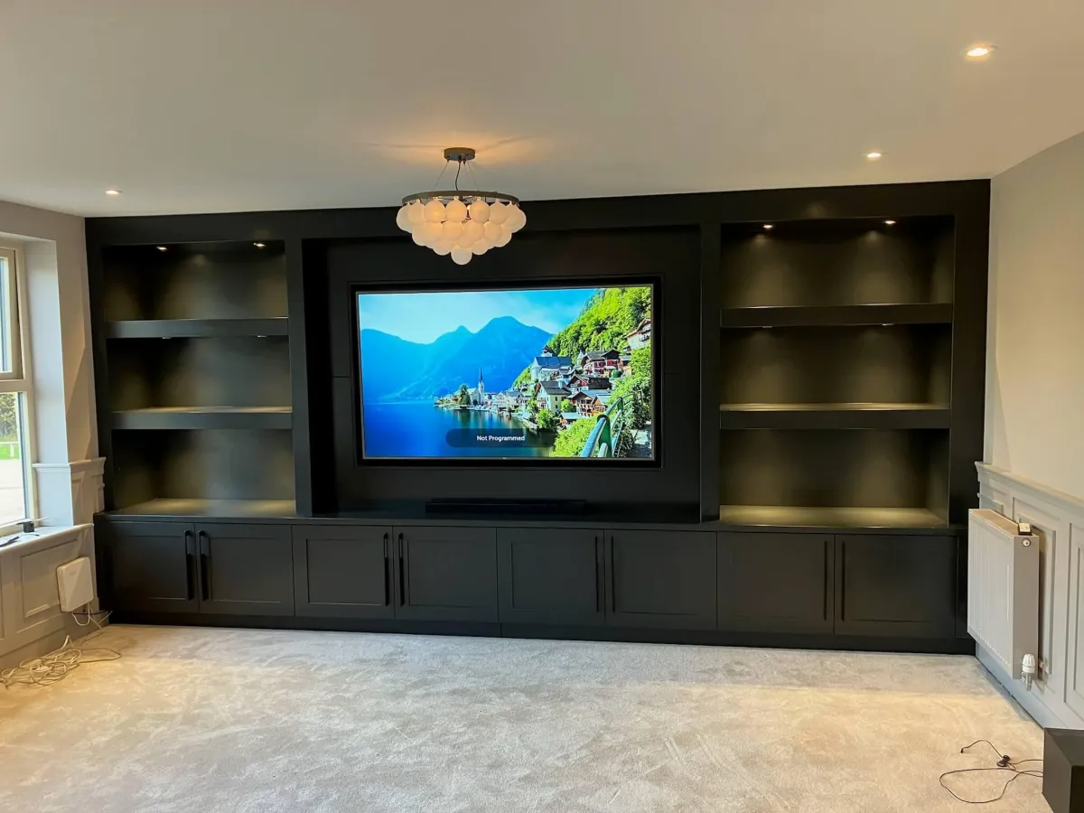 Luxury black media wall unit with built-in TV display, illuminated shelving, and base cabinets