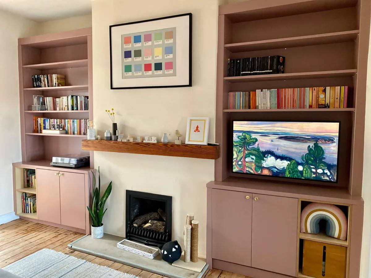 Dusty pink built-in alcove units with floor to ceiling bookshelves, cabinets & integrated TV display