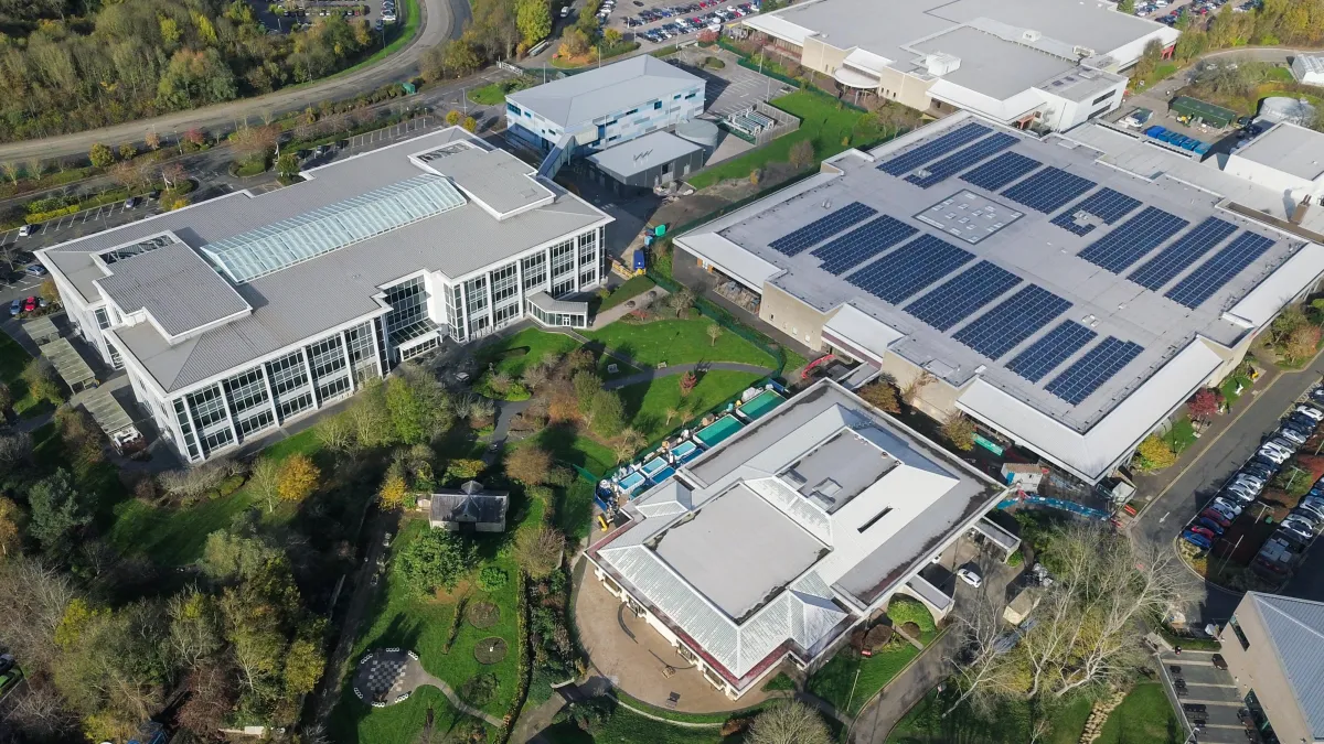 Aerial view of a commercial complex with rooftop solar panel arrays installed on multiple buildings, showcasing large-scale solar energy integration in a business district.