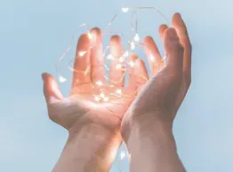 palms of hands cupped and holding sparkling light