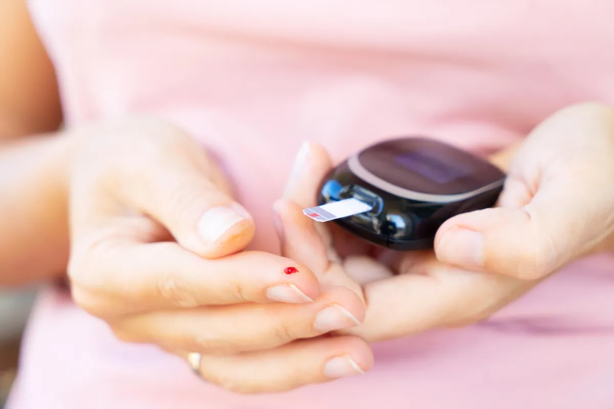 Person testing blood sugar levels with a glucose meter, highlighting diabetes management and insulin resistance.