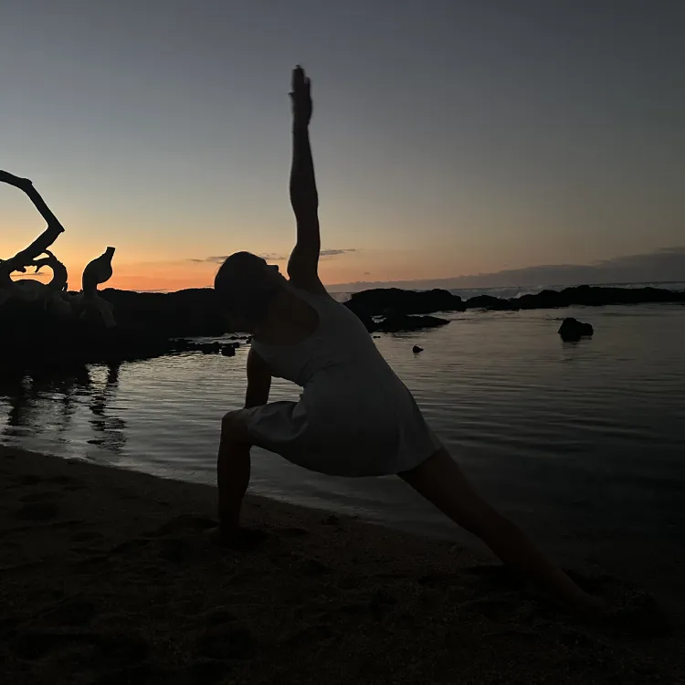 Woman in gentle sunlight with hand over heart, representing feminine intelligence, emotional rhythm, and integrative healing at ReWildHer Health.