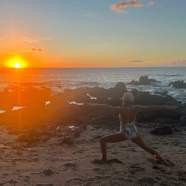 Woman in gentle sunlight with hand over heart, representing feminine intelligence, emotional rhythm, and integrative healing at ReWildHer Health.