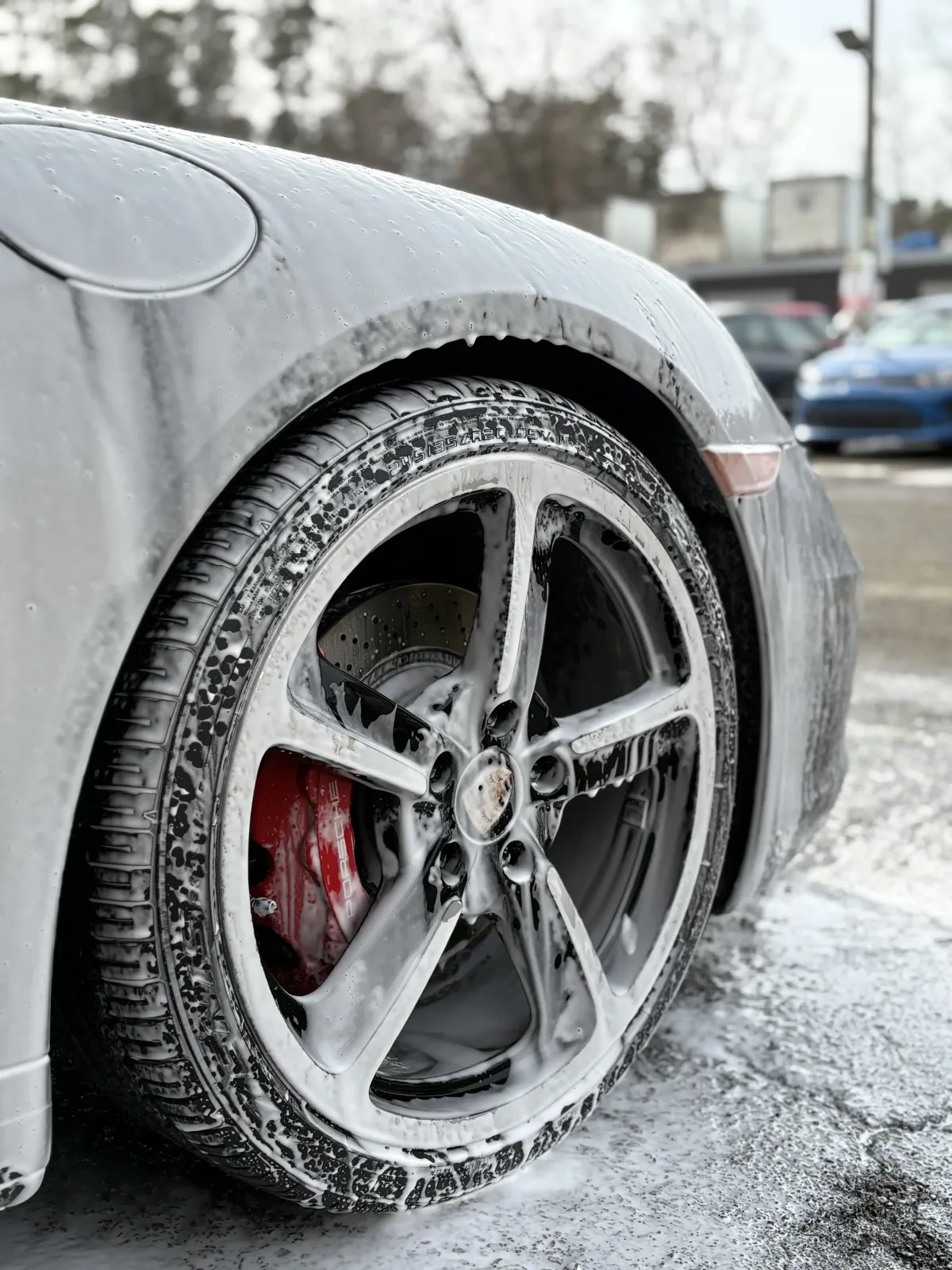Closeup image of a Porsche receiving a foam bath during an exterior detailing 