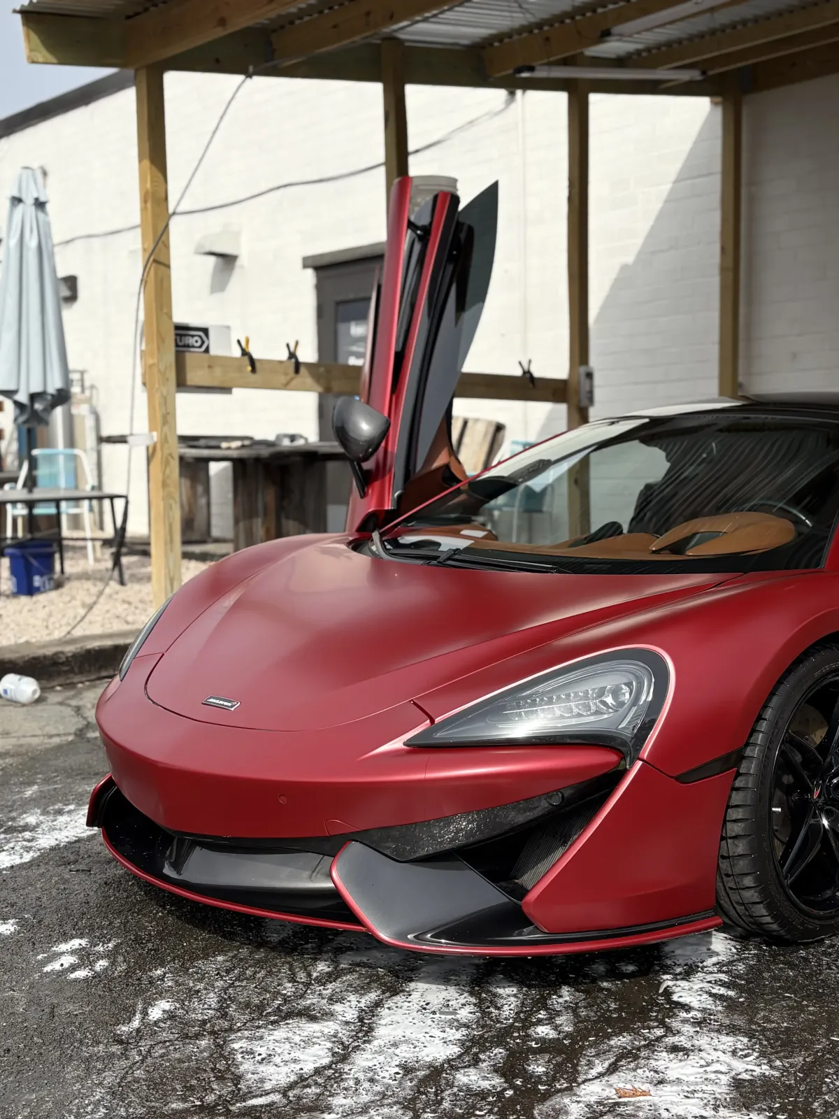 A red McLaren with the passenger side door open after a professional full detailing