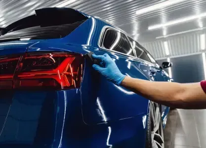 Up close shot of a Polish Plus Detailing employee applying a ceramic coating on a blue car, showcasing attention to detail and professional ceramic coating work.