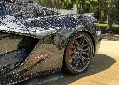 A black Corvette getting a foam bath during an exterior detailing service