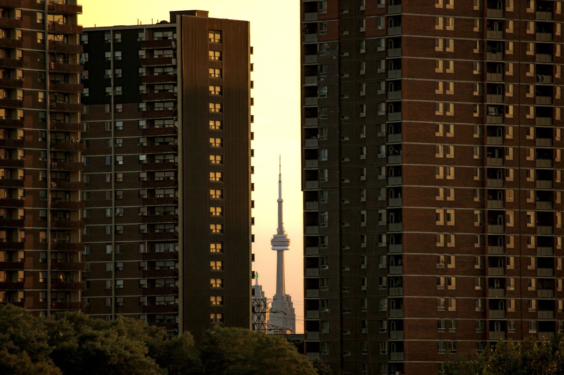 CN Tower framed between brick apartment towers in downtown Toronto at sunset