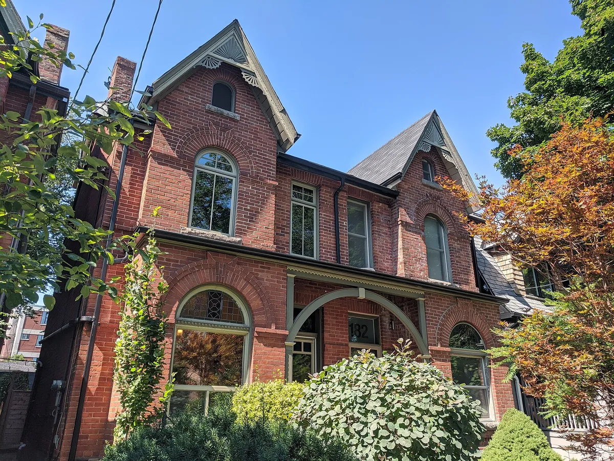 Pair of red brick semi detached houses with gables and arched windows in Leslieville, Toronto