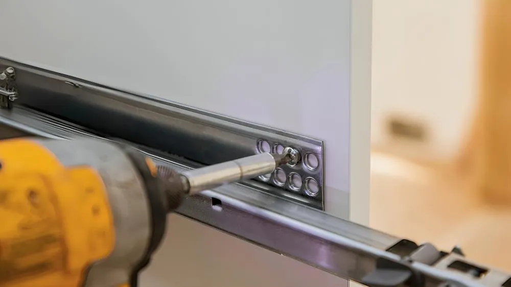 San Marcos Handyman drills in hardware for kitchen drawers.