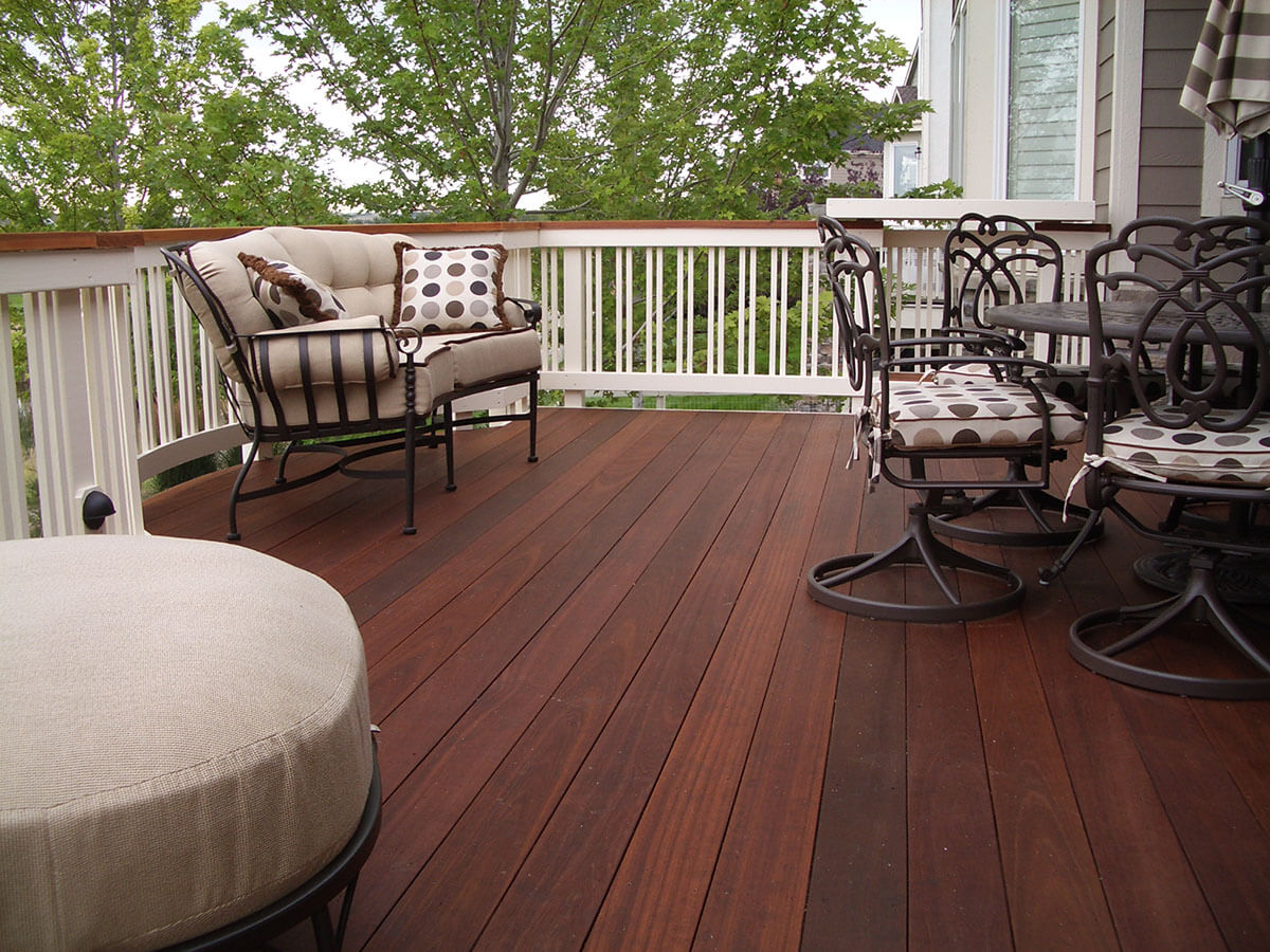 Outdoor deck featuring a comfortable seating area with a cushioned loveseat and patterned chairs, showcasing Copeland Painting's professional deck staining services for enhanced appearance and protection.