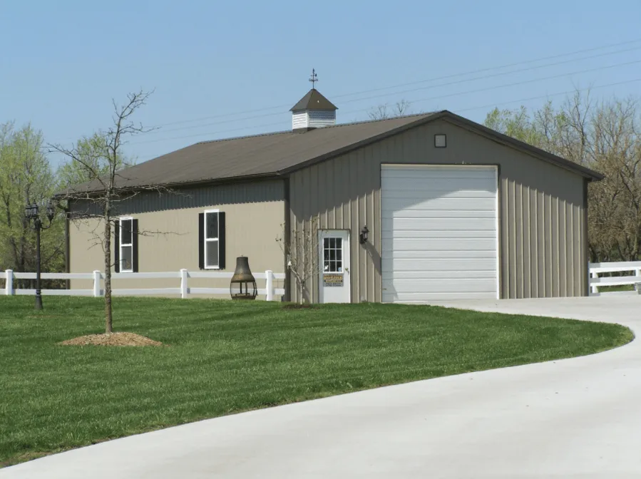 Metal building with a garage door and cupola, surrounded by green grass and trees, representing exterior painting services by Copeland Painting in Paducah, Kentucky.