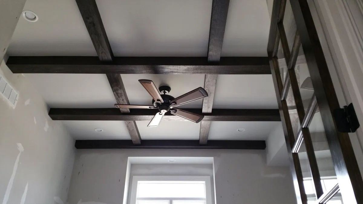 Ceiling with dark wooden beams and a ceiling fan, showcasing a freshly painted interior space in a Paducah home.