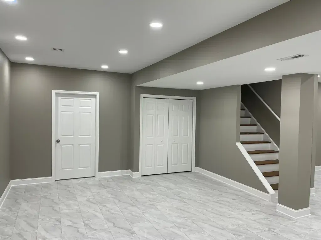 Interior of a freshly painted basement featuring light gray walls, white doors, and modern recessed lighting, highlighting the transformation and clean finish provided by Copeland Painting's interior services in Mayfield, KY.