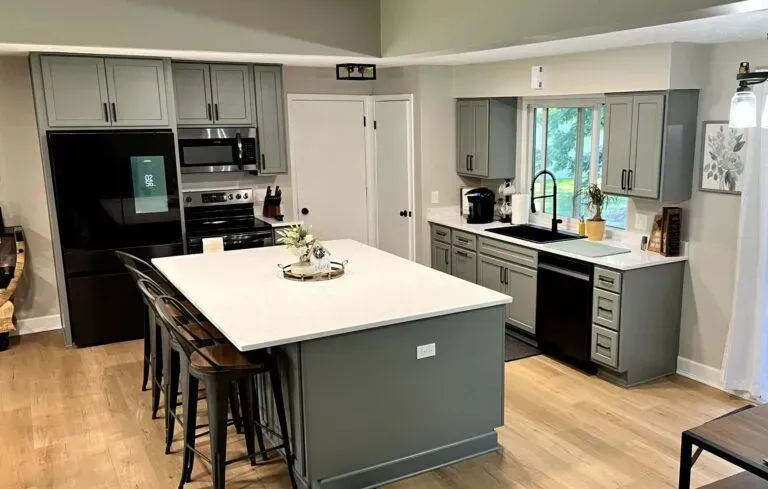 Modern kitchen featuring gray cabinetry, white countertops, and stainless steel appliances, showcasing a clean and inviting space ideal for Copeland Painting's cabinet painting services.